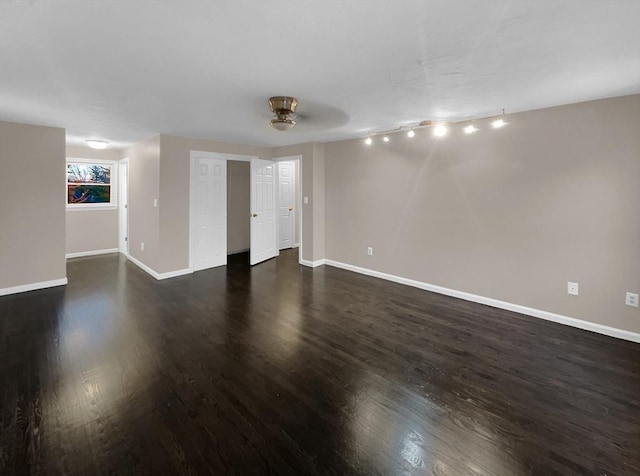 spare room featuring baseboards and dark wood finished floors