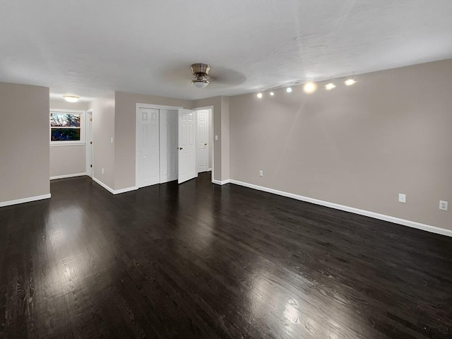 empty room featuring dark wood-style flooring and baseboards