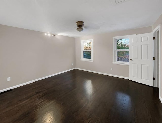 empty room with dark wood-type flooring, a ceiling fan, and baseboards