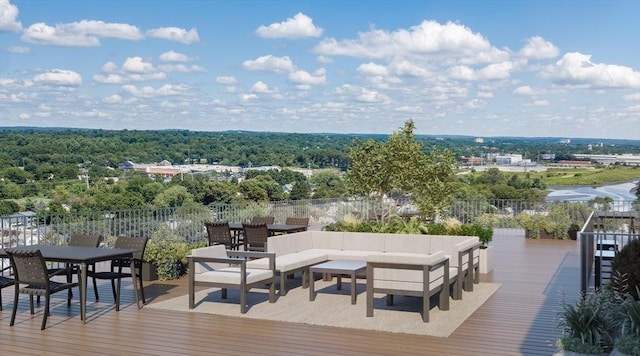 deck with outdoor dining area, a view of trees, and an outdoor living space