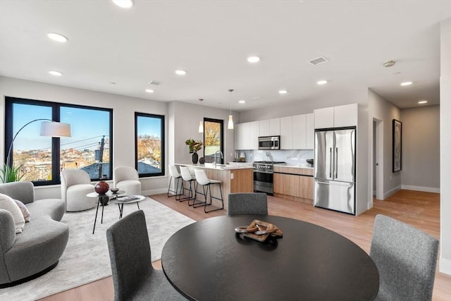 dining room featuring light wood-type flooring, baseboards, and recessed lighting