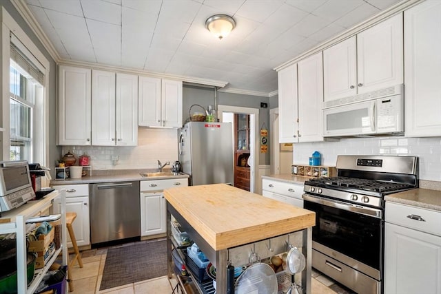69 Bradfield Ave Unit 1, Boston, MA 02131 - kitchen with appliances with stainless steel finishes, backsplash, crown molding, wooden counters, and white cabinets