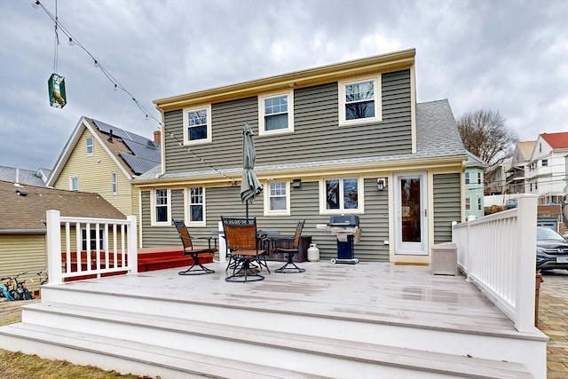 rear view of house featuring a wooden deck and outdoor dining area