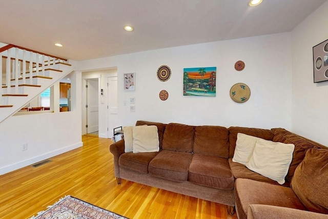 living area featuring visible vents, baseboards, light wood-style flooring, recessed lighting, and stairs