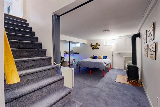 bedroom featuring a wood stove, carpet, and baseboards