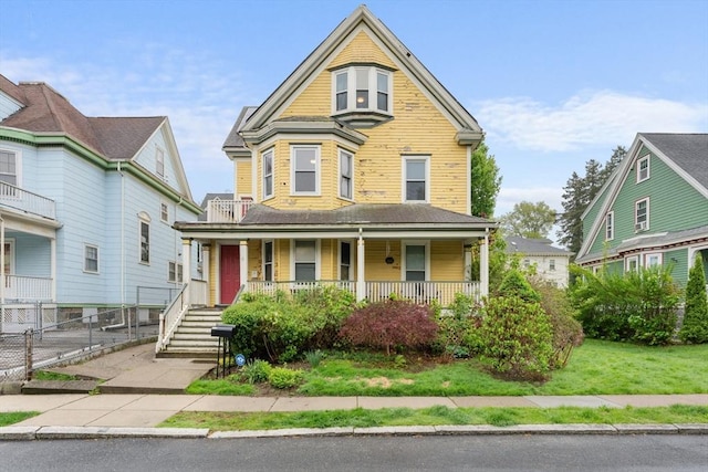 victorian house featuring covered porch and fence