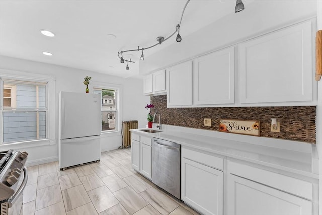 kitchen with appliances with stainless steel finishes, a sink, white cabinets, decorative backsplash, and recessed lighting