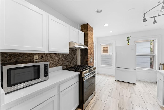 kitchen featuring stainless steel appliances, under cabinet range hood, tasteful backsplash, white cabinets, and light countertops