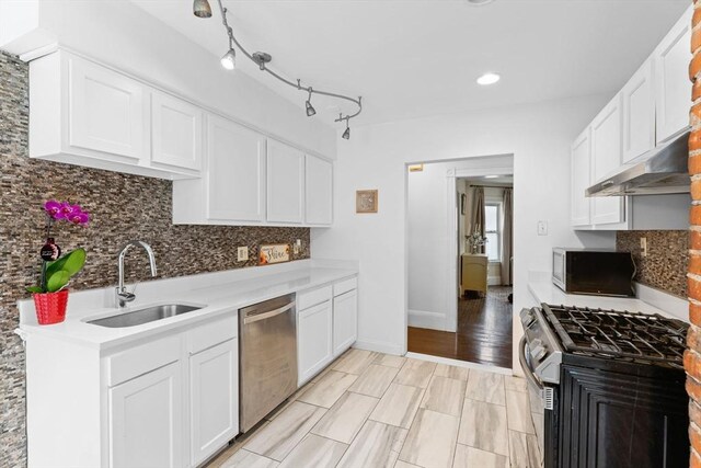 kitchen with appliances with stainless steel finishes, a sink, under cabinet range hood, decorative backsplash, and recessed lighting