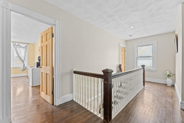 hallway with an upstairs landing, hardwood / wood-style floors, baseboards, and plenty of natural light