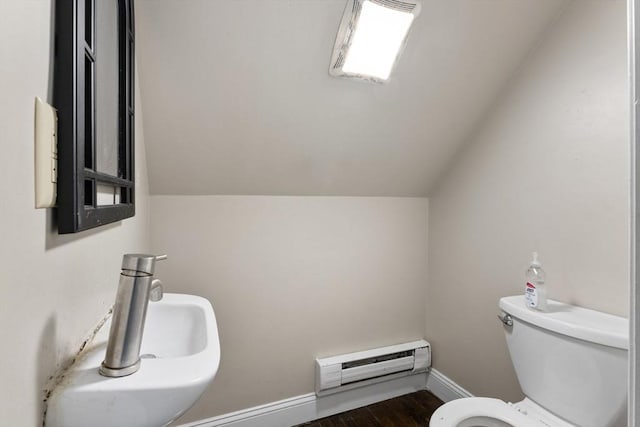 bathroom with a baseboard heating unit, lofted ceiling, toilet, baseboards, and wood finished floors