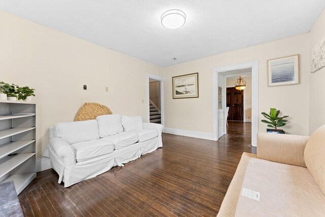 living area with baseboards, wood finished floors, and stairway