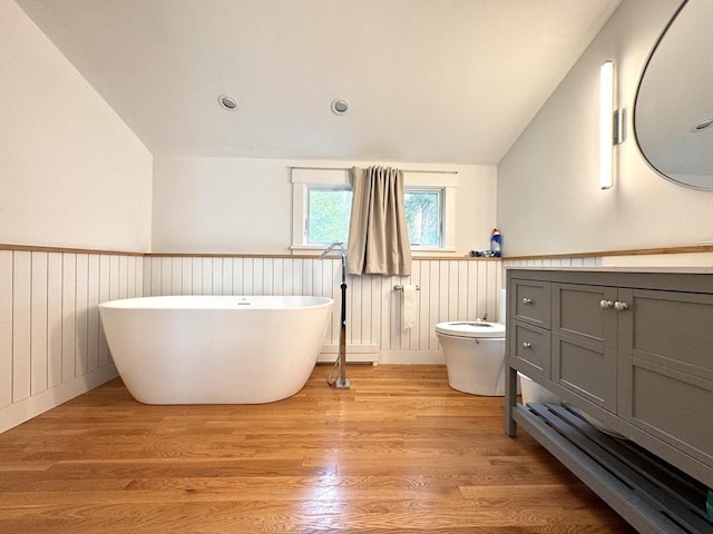 84 Walden Ter, Concord, MA 01742 - full bath featuring vaulted ceiling, vanity, a baseboard heating unit, a wainscoted wall, and a soaking tub