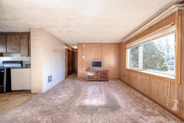 unfurnished living room featuring light colored carpet and wood walls