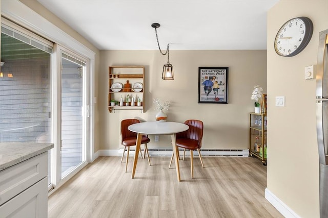 dining area featuring light wood finished floors, baseboards, and a baseboard radiator