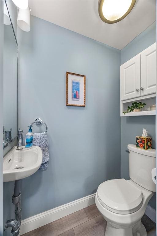 bathroom featuring a sink, baseboards, toilet, and wood finished floors