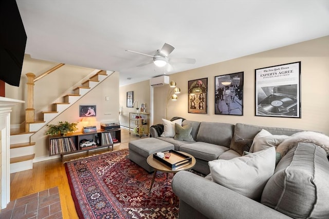 living area featuring ceiling fan, stairs, a wall unit AC, a fireplace, and wood finished floors