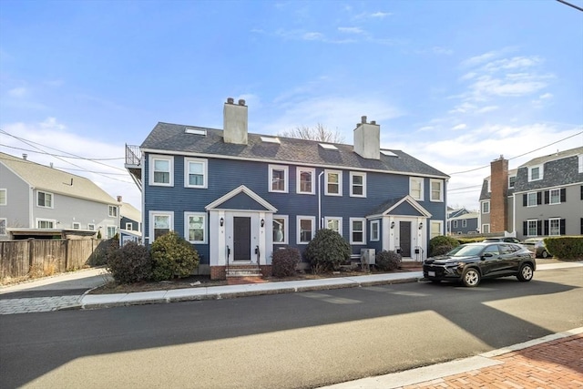 townhome / multi-family property featuring a chimney and fence