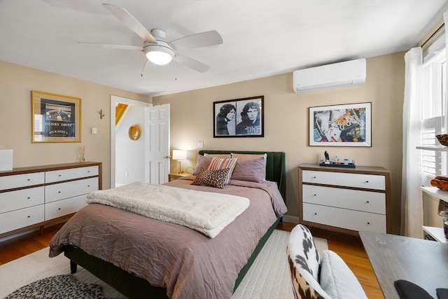 bedroom featuring a ceiling fan, a wall unit AC, and wood finished floors