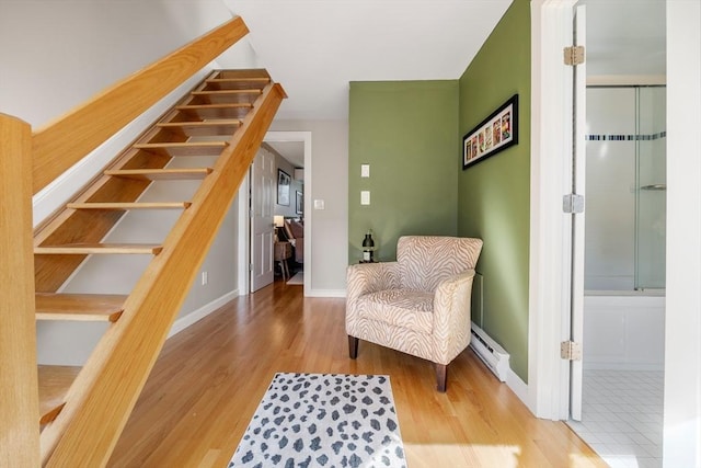 living area with baseboard heating, stairway, baseboards, and wood finished floors