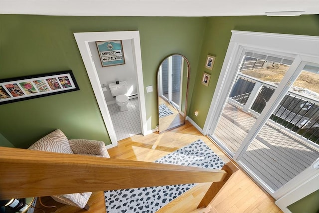 interior space with a baseboard heating unit, baseboards, and light wood-style floors