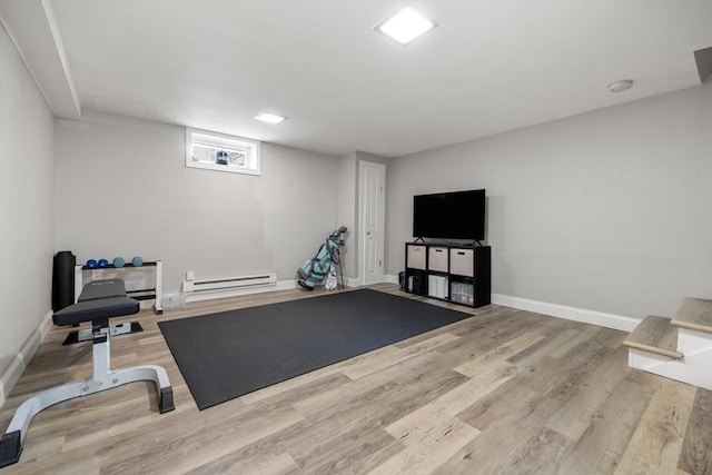 exercise room with wood finished floors, baseboards, and a baseboard radiator