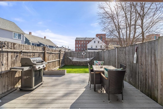 wooden deck featuring outdoor dining space, area for grilling, and a fenced backyard