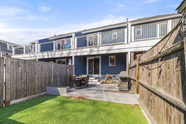 back of house featuring a yard, a patio, a balcony, and a fenced backyard