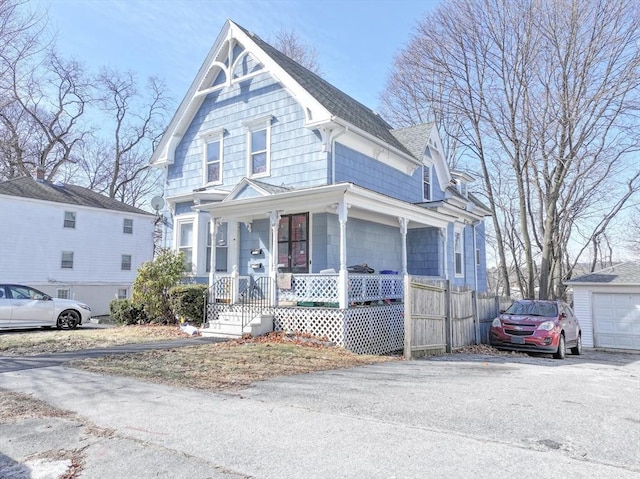 victorian home with a garage, roof with shingles, and a porch