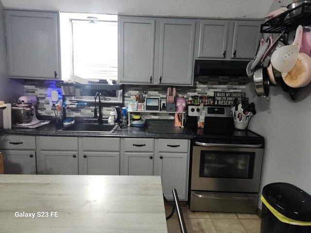 kitchen featuring tasteful backsplash, dark countertops, stainless steel electric range oven, range hood, and a sink