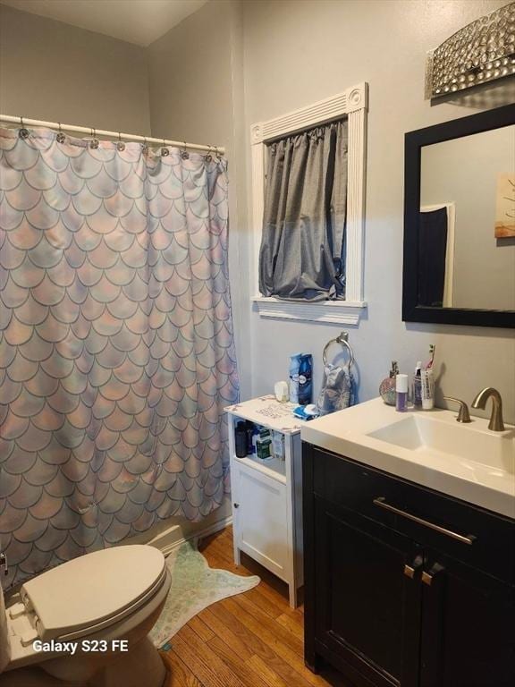 bathroom featuring shower / bath combination with curtain, toilet, vanity, and wood finished floors