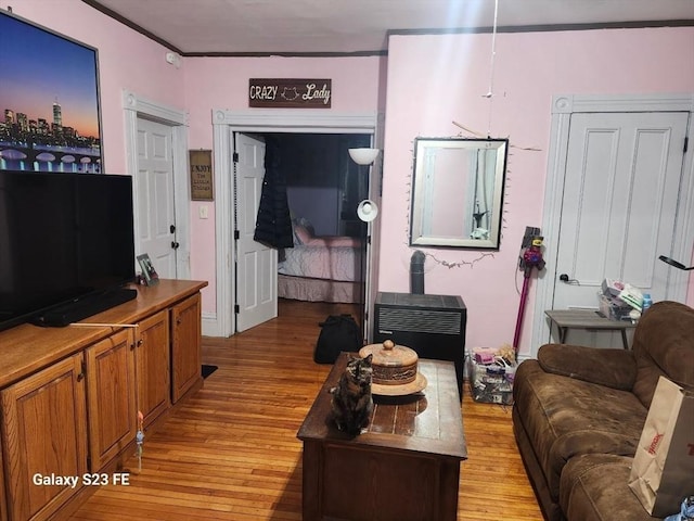 living room featuring a wood stove, light wood-style floors, and ornamental molding