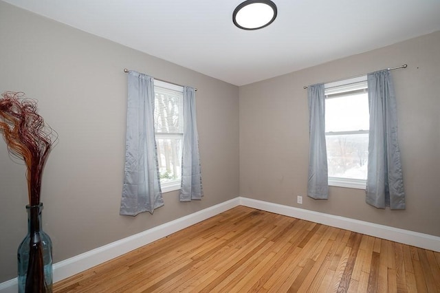 unfurnished room with a healthy amount of sunlight and hardwood / wood-style floors