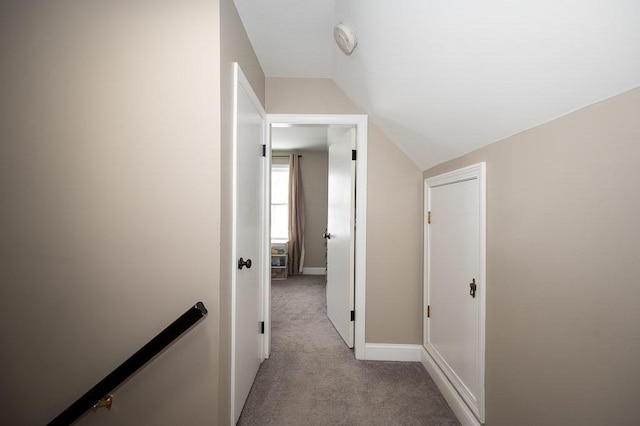 hall with lofted ceiling and light colored carpet