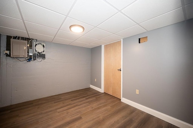 basement with wood-type flooring, electric panel, and a drop ceiling