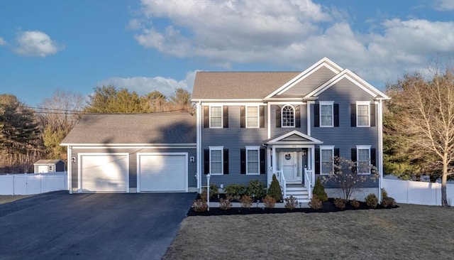 colonial inspired home with fence, driveway, and an attached garage