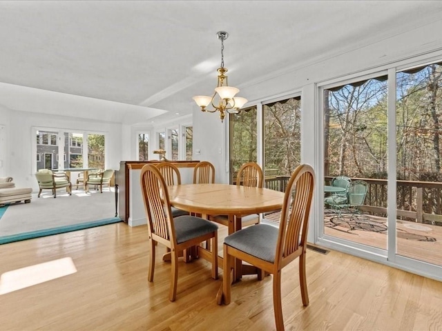 dining area with visible vents, a chandelier, and light wood finished floors