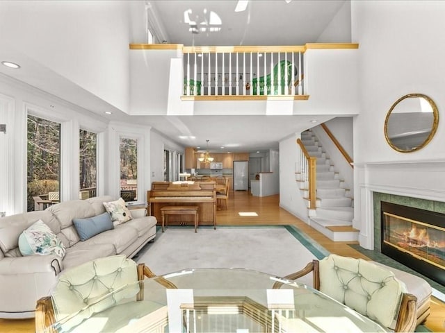 living room with stairs, a high ceiling, light wood-style flooring, and a fireplace