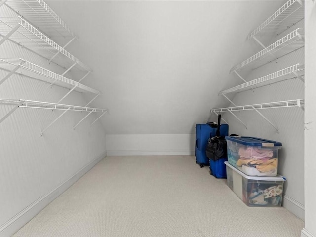 walk in closet with carpet floors and vaulted ceiling