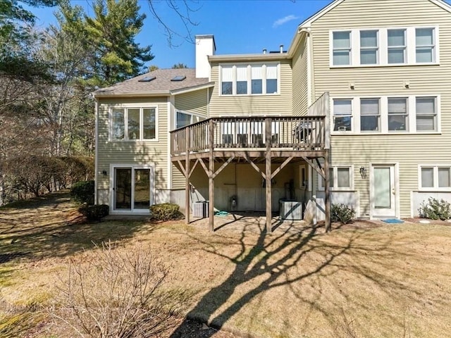 back of property featuring cooling unit, a yard, a deck, and a chimney