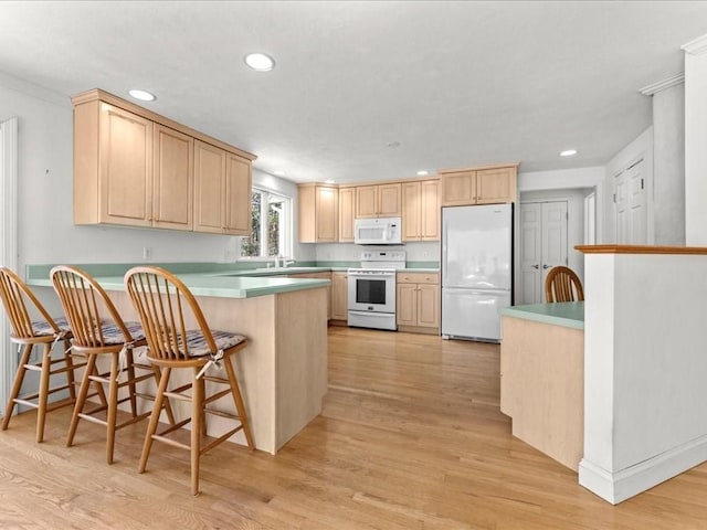 kitchen with white appliances, light brown cabinets, and light wood finished floors