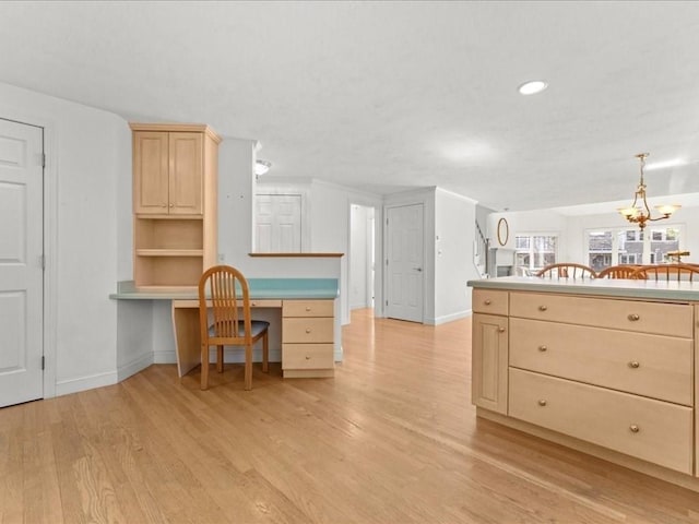 kitchen with light brown cabinetry, built in study area, light wood-type flooring, and baseboards