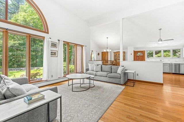 75 Winter St, Hopkinton, MA 01748 - living area featuring a baseboard heating unit, high vaulted ceiling, a chandelier, light wood-style floors, and a ceiling fan