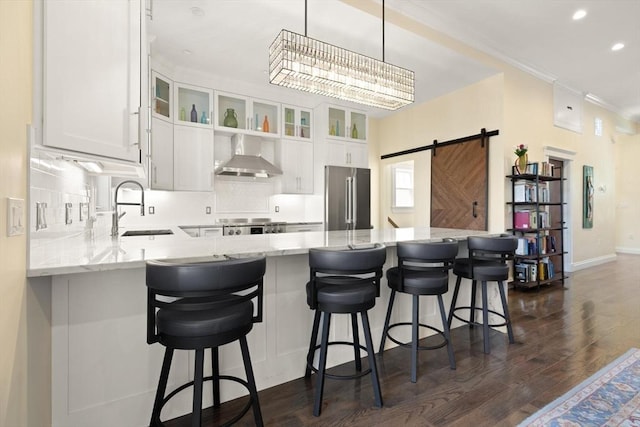 125 Heath St, Somerville, MA 02145 - kitchen featuring high end fridge, wall chimney exhaust hood, a barn door, a peninsula, and dark wood-type flooring