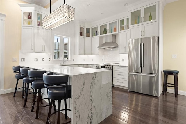 125 Heath St, Somerville, MA 02145 - kitchen featuring stainless steel appliances, wall chimney range hood, a kitchen breakfast bar, dark wood-style floors, and ornamental molding