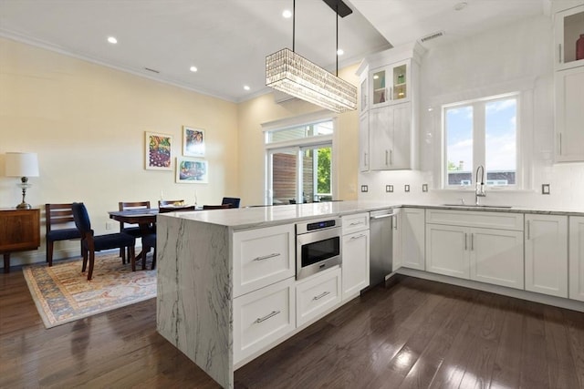 125 Heath St, Somerville, MA 02145 - kitchen with a peninsula, stainless steel appliances, dark wood-type flooring, crown molding, and light stone counters