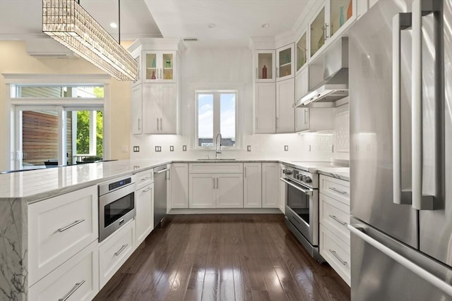 125 Heath St, Somerville, MA 02145 - kitchen with stainless steel appliances, a peninsula, extractor fan, light stone countertops, and white cabinets