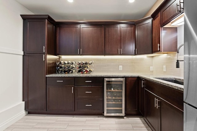 125 Heath St, Somerville, MA 02145 - kitchen with wine cooler, light stone counters, tasteful backsplash, dark brown cabinetry, and light wood-style floors