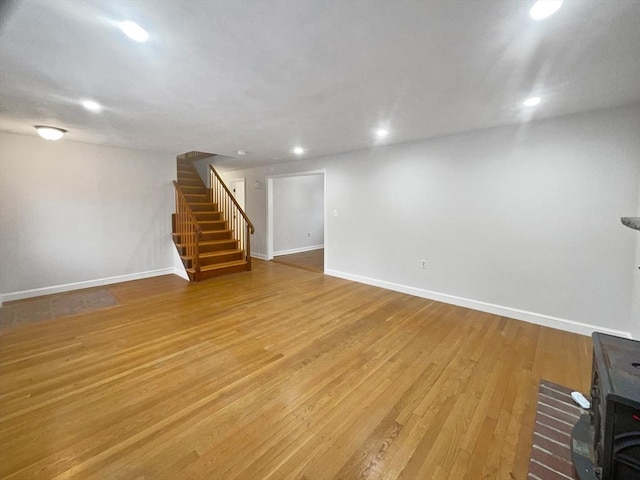 basement with a wood stove and hardwood / wood-style floors