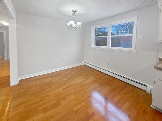 empty room featuring a baseboard heating unit, light hardwood / wood-style flooring, and a notable chandelier